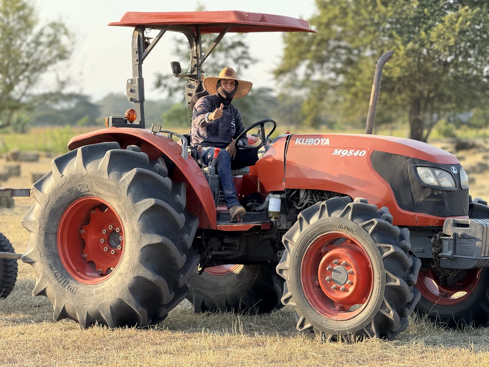 Tractorista con sombrero al mando de un equipo durante una jornada en el campo.